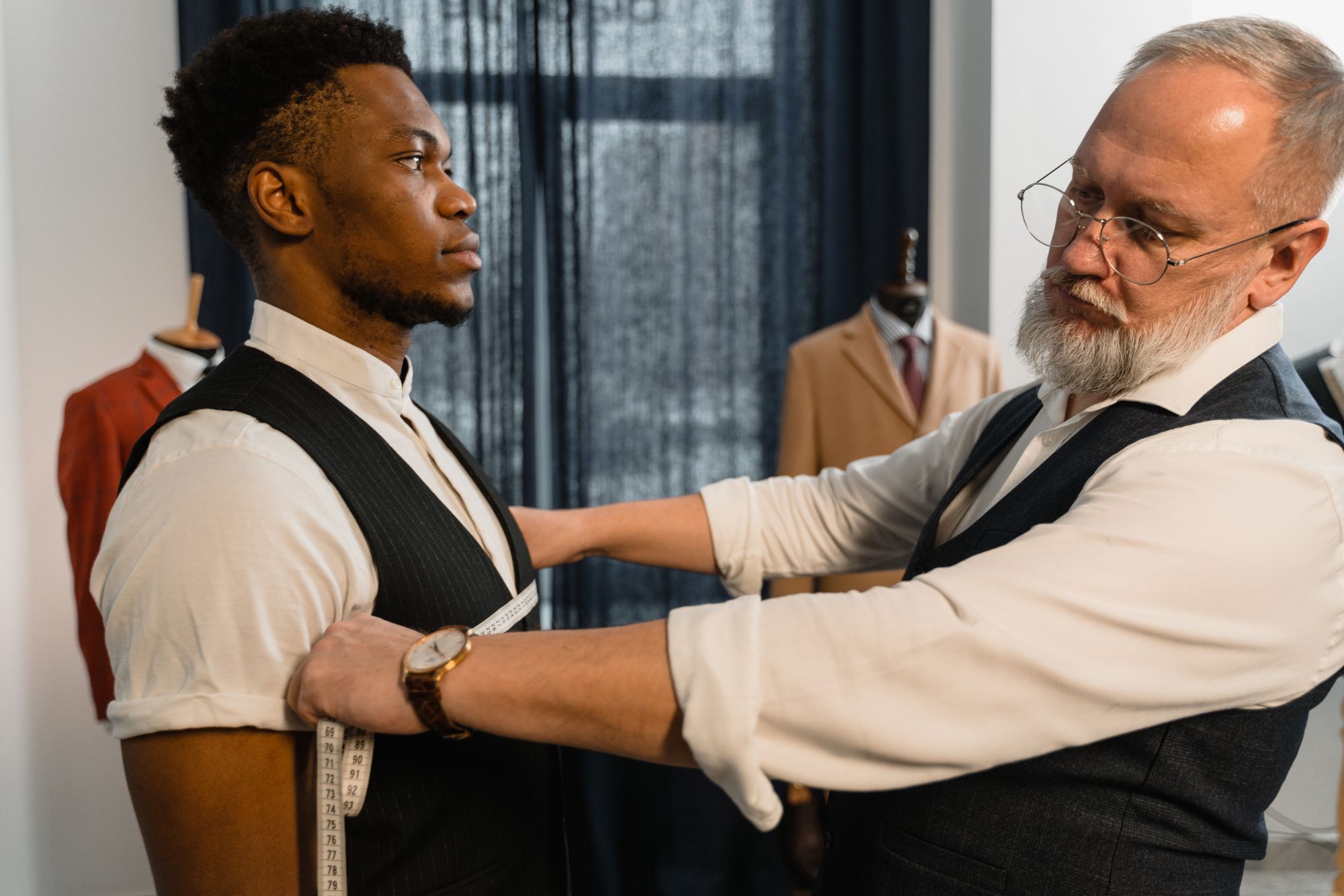 Tailor taking a client's measurements in a menswear workshop