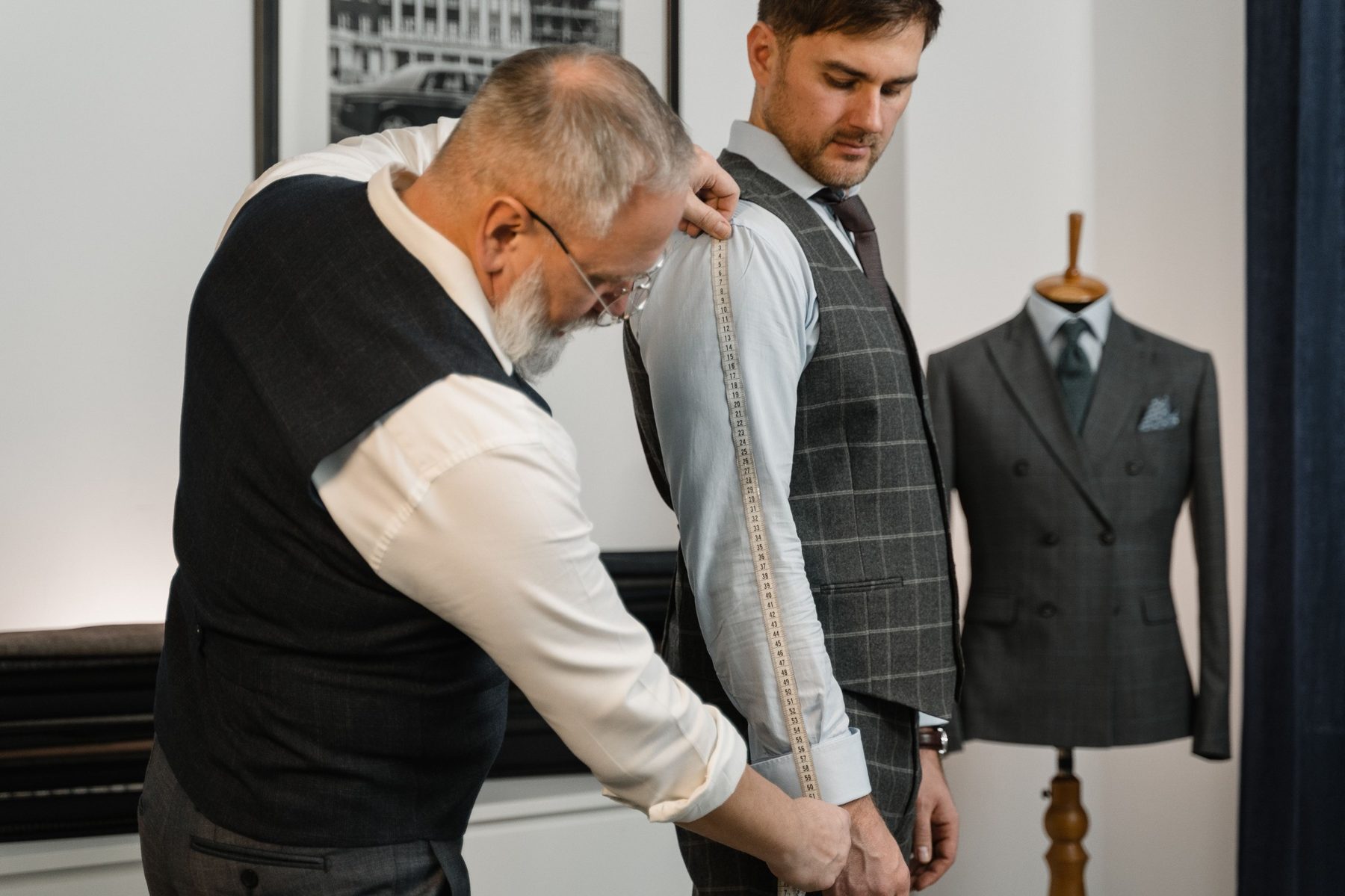 All Suits tailor adjusting a customer's check waistcoat during a fitting