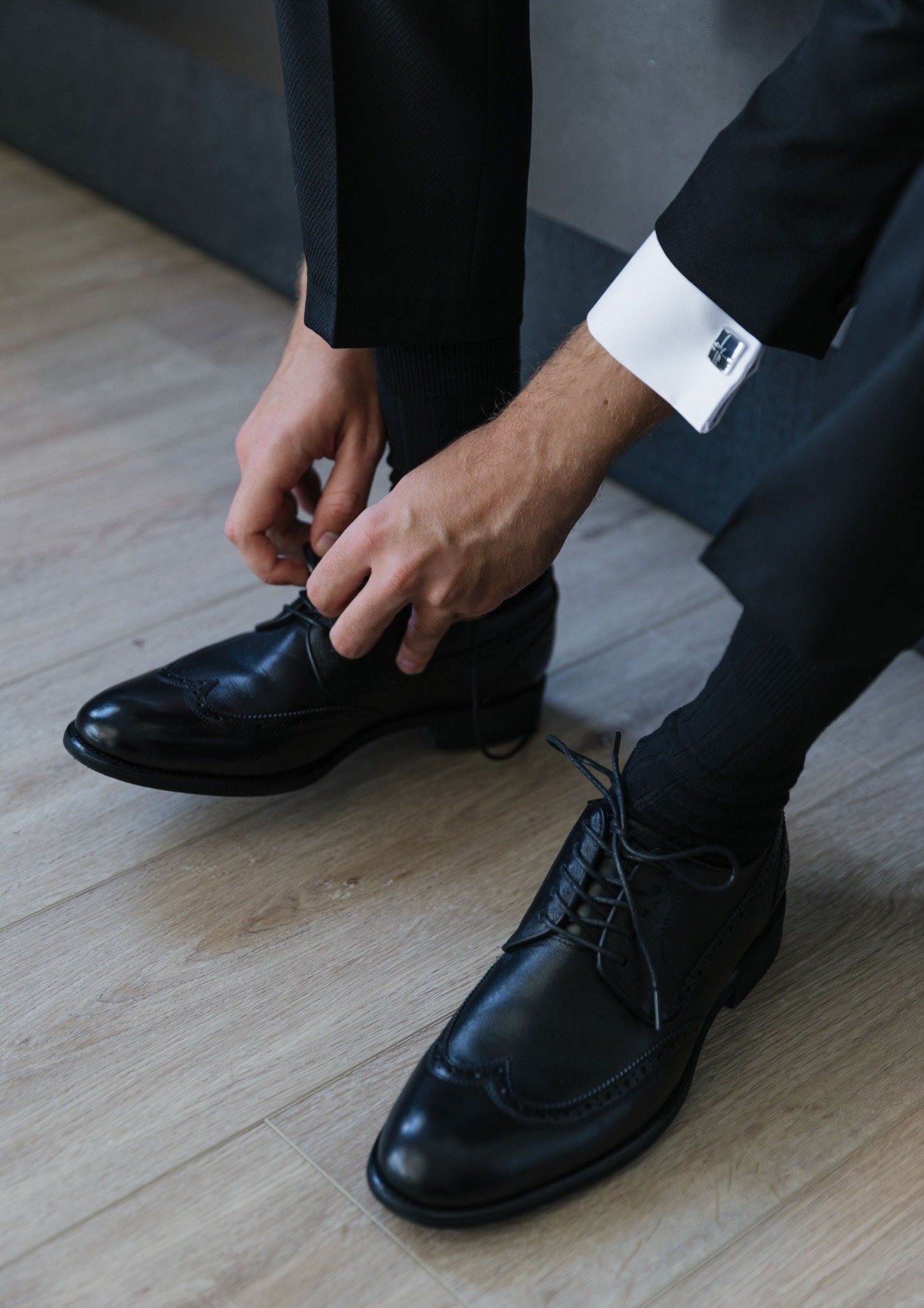Man fastening black formal shoes with a suit and cufflinks